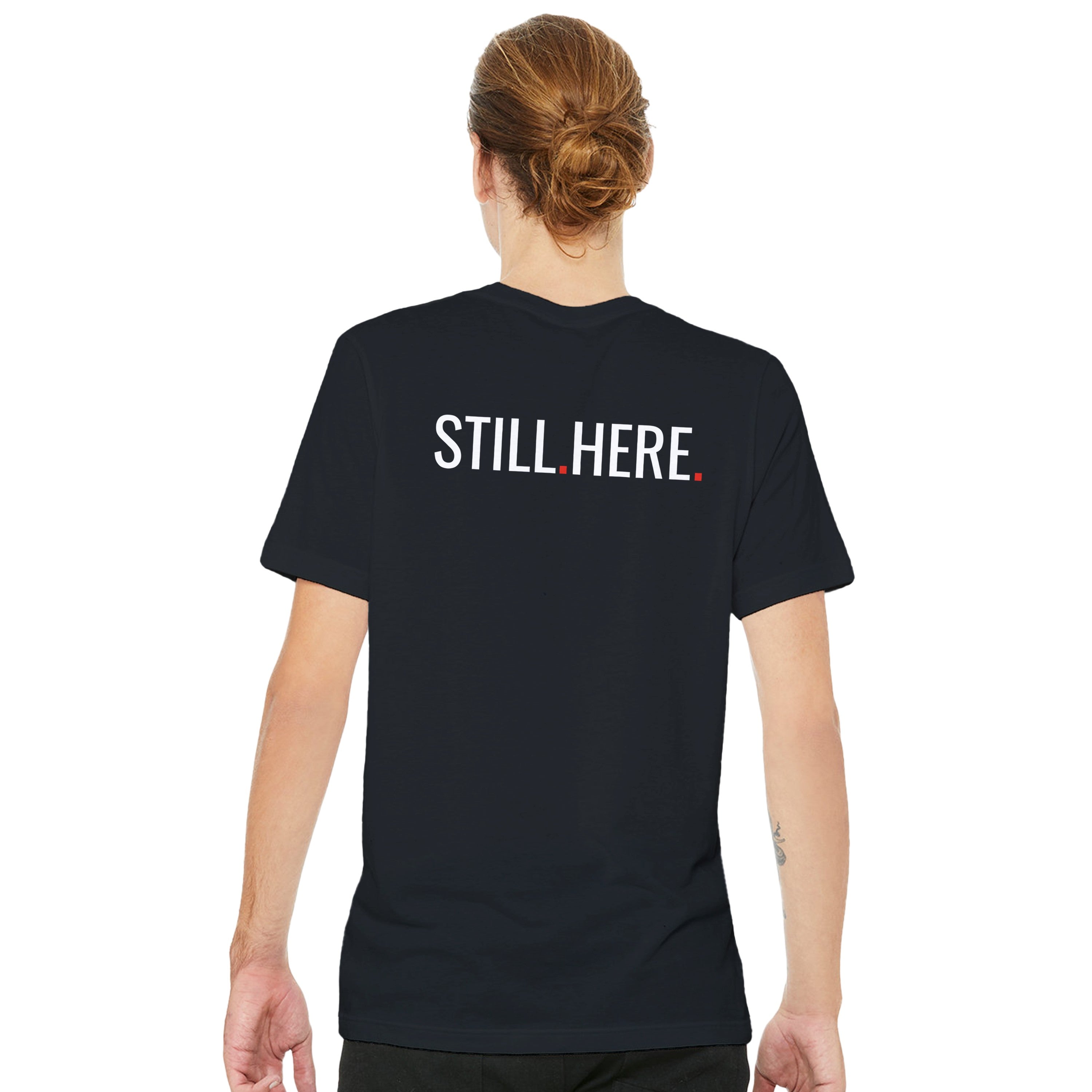 Person wearing a black t-shirt with 'STILL HERE' text on the back, standing against a white background